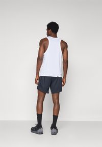 Men's athletic outfit featuring a white sleeveless tank top and dark shorts, paired with black socks and shoes. Smooth fabric, relaxed fit.