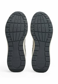 Podeszwa butów wykonana z teksturowanej czarnej gumy z głębokim bieżnikiem, z jasnoszarym akcentem po boku oraz wytłoczonym logo "TOMMY JEANS."