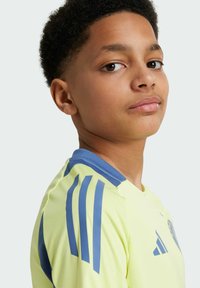 Maillot de football pour jeunes en tissu léger, jaune vif avec des accents bleus, et trois bandes bleues sur les épaules.