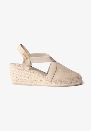 Smėlio spalvos espadrilės platformos sandalai su kryžminėmis elastingomis juostelėmis, pintu džuto viduriniu padu ir apvaliu pirštu. Audinių paviršius yra tekstūruotas.