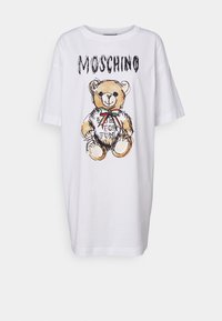 Biała, oversize t-shirt z grafiką niedźwiedzia, zdobioną czerwoną i zieloną wstążką. Wzór zawiera tekst "# FOR FUN" w kolorze czarnym.