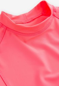 Hellrosa dehnbare Stoff, glatte Textur, mit hohem Kragen und flachen Nähten. Entworfen für Komfort und Flexibilität in Sportbekleidung.