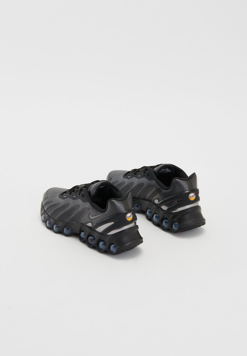 Zapatillas deportivas negras con un diseño elegante, que presentan una parte superior texturizada, punta redondeada y suela de burbuja para mayor amortiguación. Marca notable en el talón.