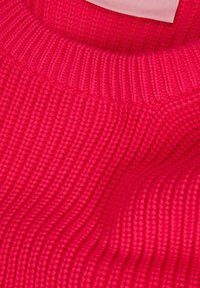 Pullover di maglia rosa brillante con texture a coste e scollatura rotonda, con un'etichetta di tessuto liscia parzialmente visibile.