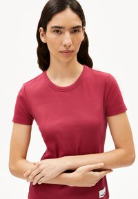 Geripptes, kurzärmliges T-Shirt in kräftigem Pink. Runder Ausschnitt, weiche Textur, taillierte Passform, mit einem kleinen Logo-Etikett auf der unteren rechten Seite.