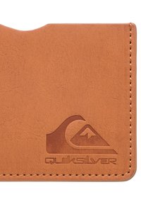 Tan leather wallet with a textured finish, featuring an embossed Quiksilver logo and a rounded cutout at the top edge. Edges are stitched.