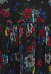 Černá síťovina zdobená barevnými květinovými vzory v červené, modré a bílé barvě, s volánkovou texturou podél horního okraje.