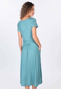 Türkises Kleid mit floralem Muster, kurzen Ärmeln und taillierter Taille. Die Länge reicht bis zur Mitte der Waden, mit seitlichen Taschen, die in das Design integriert sind.