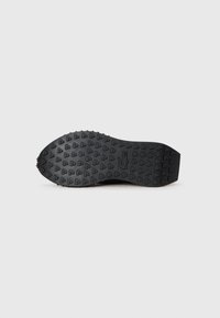 Black rubber shoe sole with a textured surface featuring triangular patterns and a logo embossed at the heel. Smooth and flat profile.