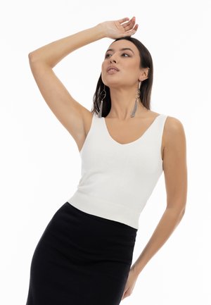 Weißes, tailliertes Tanktop mit V-Ausschnitt und breiten Trägern, kombiniert mit einem schwarzen, hoch geschnittenen Rock. Der Stoff wirkt glatt und dehnbar.