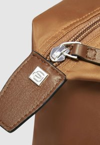 Borsa marrone in nylon con tracolla in pelle testurizzata e chiusura a cerniera in metallo argentato. Presenta una targhetta con logo sulla tracolla e una finitura liscia e lucida.