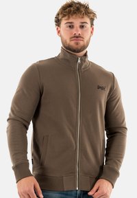 Sweat à zip marron avec un col montant, des poignets côtelés et des poches. Fabriqué en tissu doux avec une finition texturée et un logo brodé.