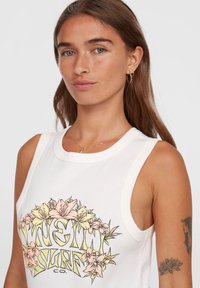 Vit ärmlös linne med en färgglad blommig grafisk design, med rosa och gula blommor samt texten "SURF CO." i ett cirkulärt mönster.
