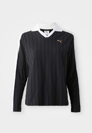 Czarna koszula polo z długim rękawem w pionowe paski, biała kołnierzyk, złote logo na klatce piersiowej i kontrastujące białe rękawy. Miękka tekstura materiału.