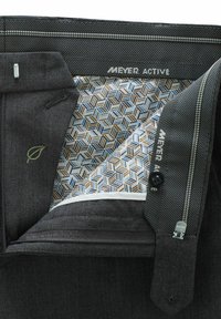 Pantalons gris foncé avec un motif en chevrons, dotés d'une doublure à motifs géométriques en bleu et marron. Comprend des fermetures à glissière et à bouton.