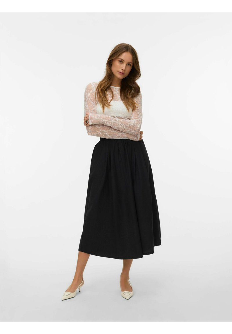 Bel zgornji del z dolgimi rokavi iz čipke s prilegočo korsetno obliko, kombiniran s črno midisečno krilom. Model nosi krem rjave čevlje z ostrimi konicami. Preprost, eleganten dizajn.