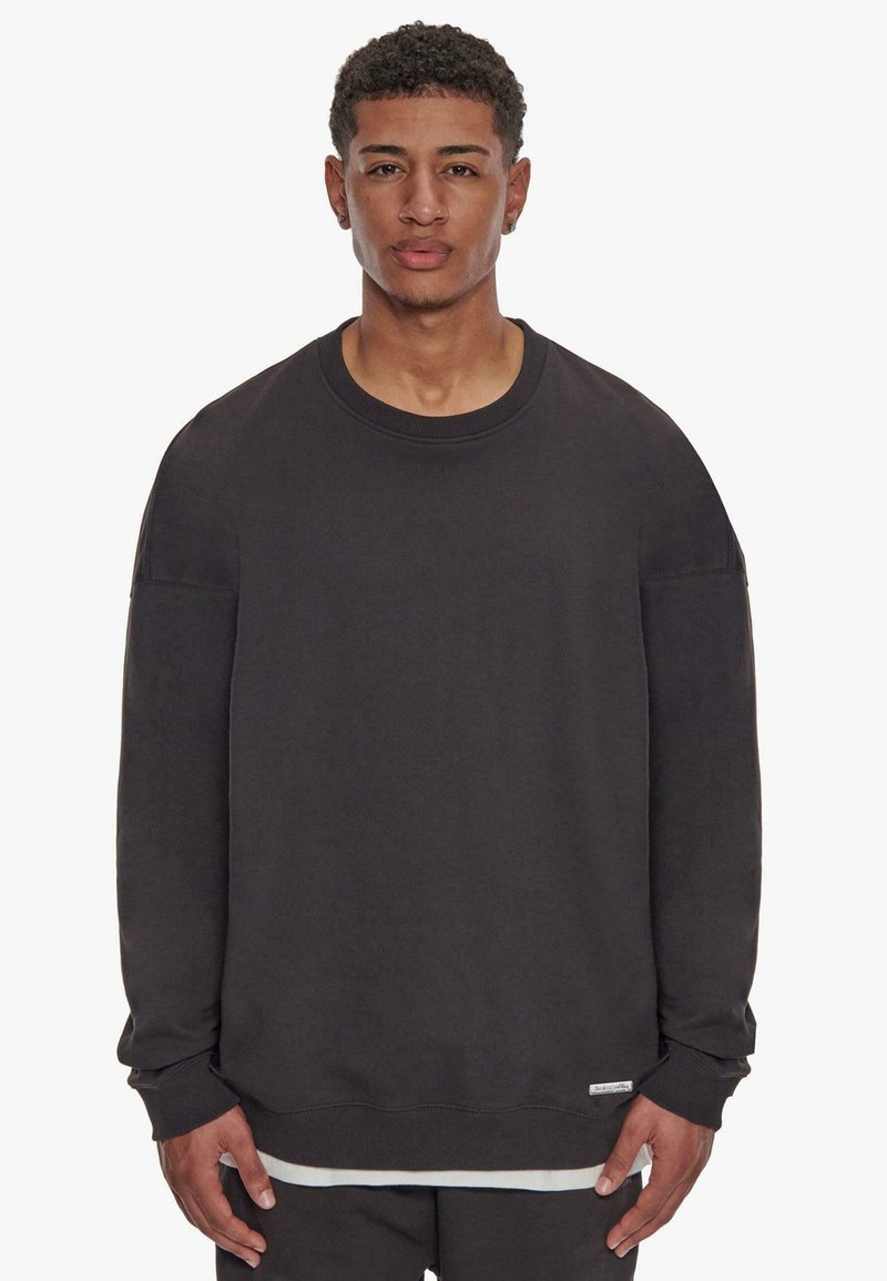 Sort crewneck sweatshirt med lange ærmer, lavet af blødt stof, med ribbede manchetter og kant, samt et lille logo mærke nederst til venstre.