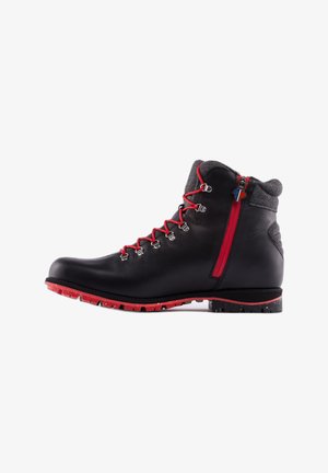 Bota de senderismo de cuero negro con cordones y suela rojos, cuello acolchado gris y cremallera roja en el lateral, mostrada de perfil.