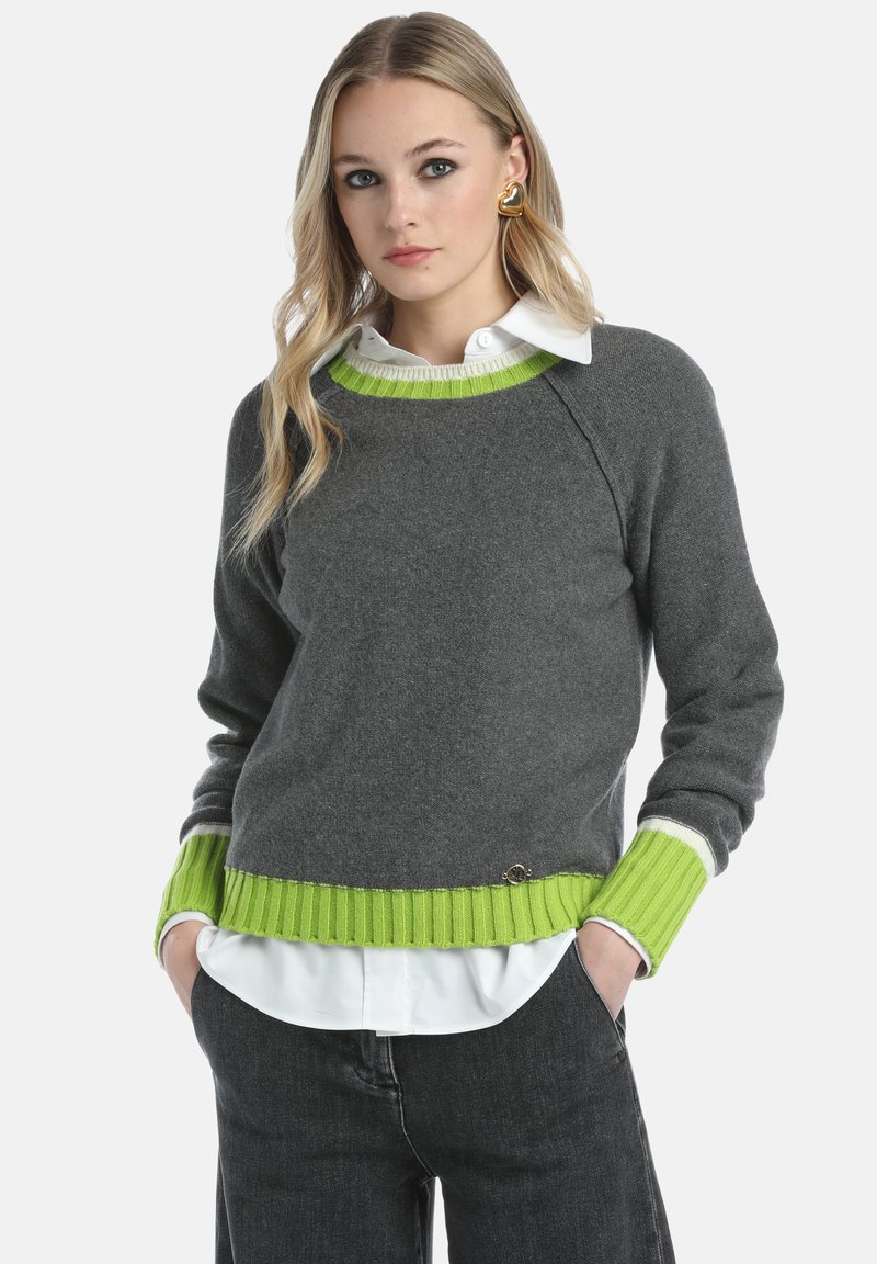 Pull en maille gris avec des accents côtelés vert lime au niveau du col et de l'ourlet, présentant une chemise blanche à col superposée en dessous.