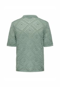 Polo majica kratkih rukava u mint zelenoj boji s teksturiranim, pletenim uzorkom koji sadrži dijamantske oblike i rebrastim ovratnikom.