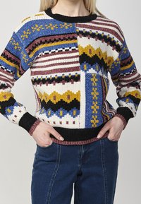 Maglione lavorato a maglia con blocchi multicolori a motivo in blu, giallo, bordeaux e nero. Presenta una scollatura e polsini a costine neri.