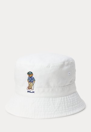 Bob blanc avec un golfeur brodé portant une chemise bleue et un pantalon beige, tenant un club de golf, avec le texte "RLX" en dessous.