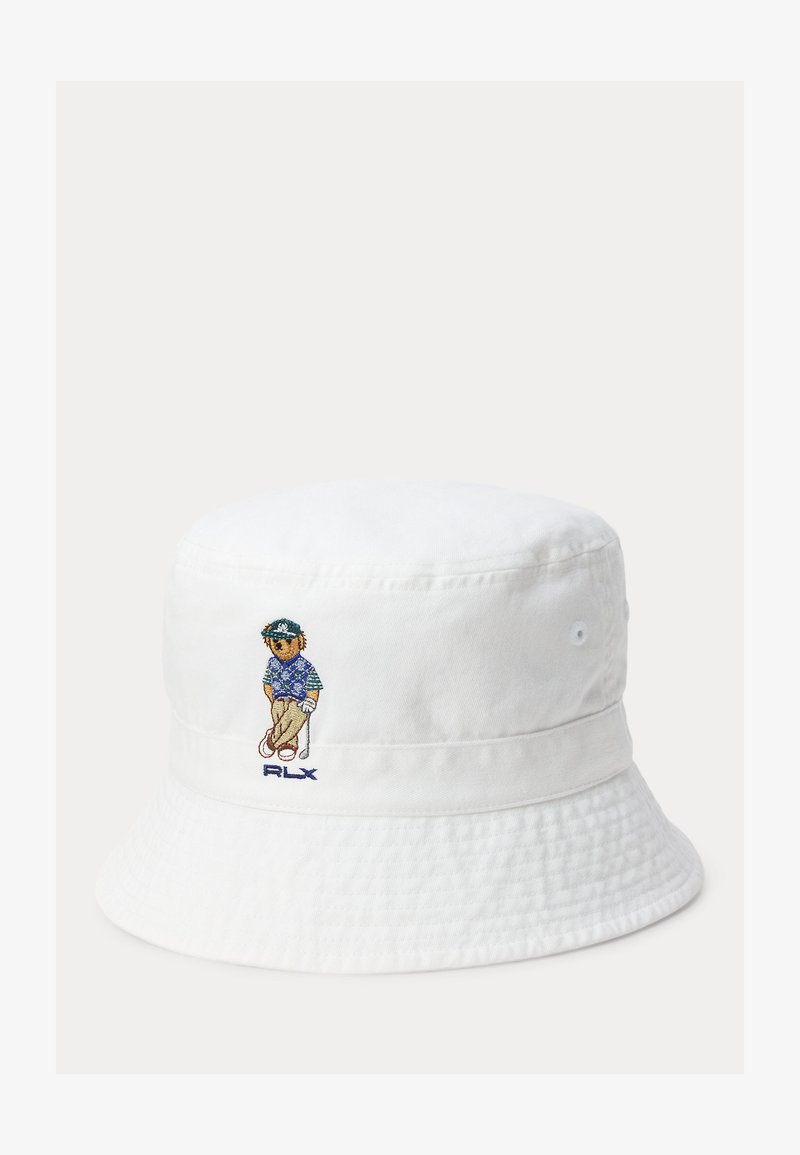 Άσπρο καπέλο κουβά με κεντημένο γκολφέρ σε μπλε πουκάμισο και μπεζ παντελόνι, κρατώντας μπαστούνι του γκολφ, και το κείμενο «RLX» από κάτω.