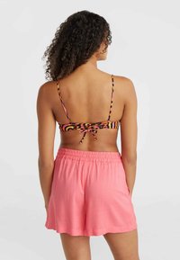 Multebarvna halter bikini zgornji del z tankimi naramnicami, ki ima vezanje na hrbtu. V kombinaciji z ohlapnimi, roza kratkimi hlačami z elastičnim pasom.