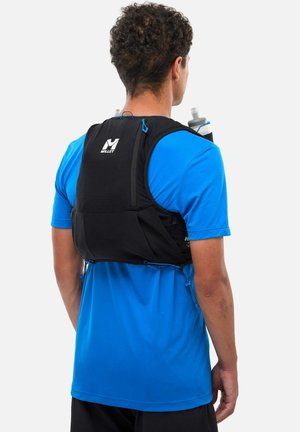 Homme portant un gilet d'hydratation Millet noir avec deux bouteilles d'eau, par-dessus un t-shirt bleu à manches courtes, vu de dos sur un fond blanc.