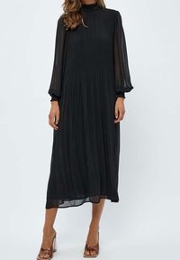 Svart, plisserad midiklänning med långa genomskinliga ärmar, hög hals och flödande silhuett. Har ett mjukt, lättviktigt tyg.