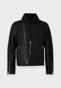 Chaqueta de cuero negra de estilo motero con cremallera frontal asimétrica, tres bolsillos con cremallera, cremalleras en los puños de las mangas y un suave collar de forro polar.