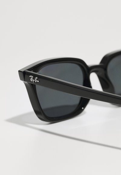 Черни слънчеви очила Ray-Ban с квадратни рамки, тъмни лещи и лъскаво покритие. Имат странично лого и прави изчистени шия.