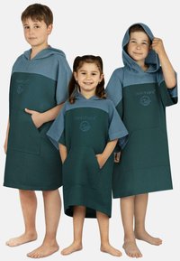 Hooded Bad Ponchos aus blauer und grüner Waffelware mit einer Fronttasche und einem Logo, getragen von drei Kindern unterschiedlicher Größen.