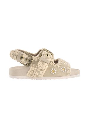 Beige åben-tå sandal med hæklede remme, justerbar spænde og små perle- og guldbelagte blomsterudsmykninger på siden.