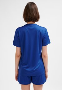 Niebieska sportowa koszulka termoaktywna z krótkim rękawem. Gładka faktura, luźny krój. W zestawie z dopasowanymi niebieskimi szortami, również wykonanymi z lekkiego materiału.