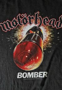 T-shirt noire avec une illustration de bombe rouge, entourée d'effets d'explosion, avec "motörhead" en police stylisée au-dessus et "BOMBER" en dessous.