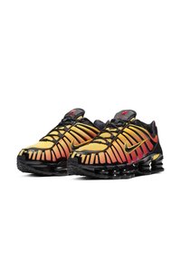 Sport shoes featuring a gradient yellow to red mesh upper, black accents, and a distinctive segmented sole for cushioning. Black laces and branding.