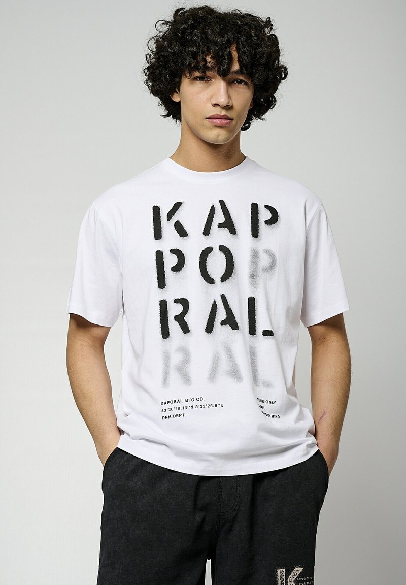 T-shirt en coton blanc avec des lettres noires audacieuses et des coordonnées. Coupe standard, manches courtes et col rond. Shorts noirs avec un accent de logo.