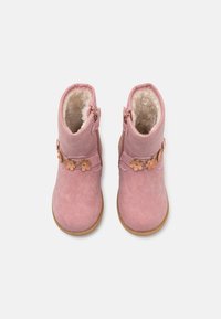 Pink ankle boots made of soft material, featuring a faux fur lining, floral accents, and a side zipper for easy wear. Flat rubber soles.