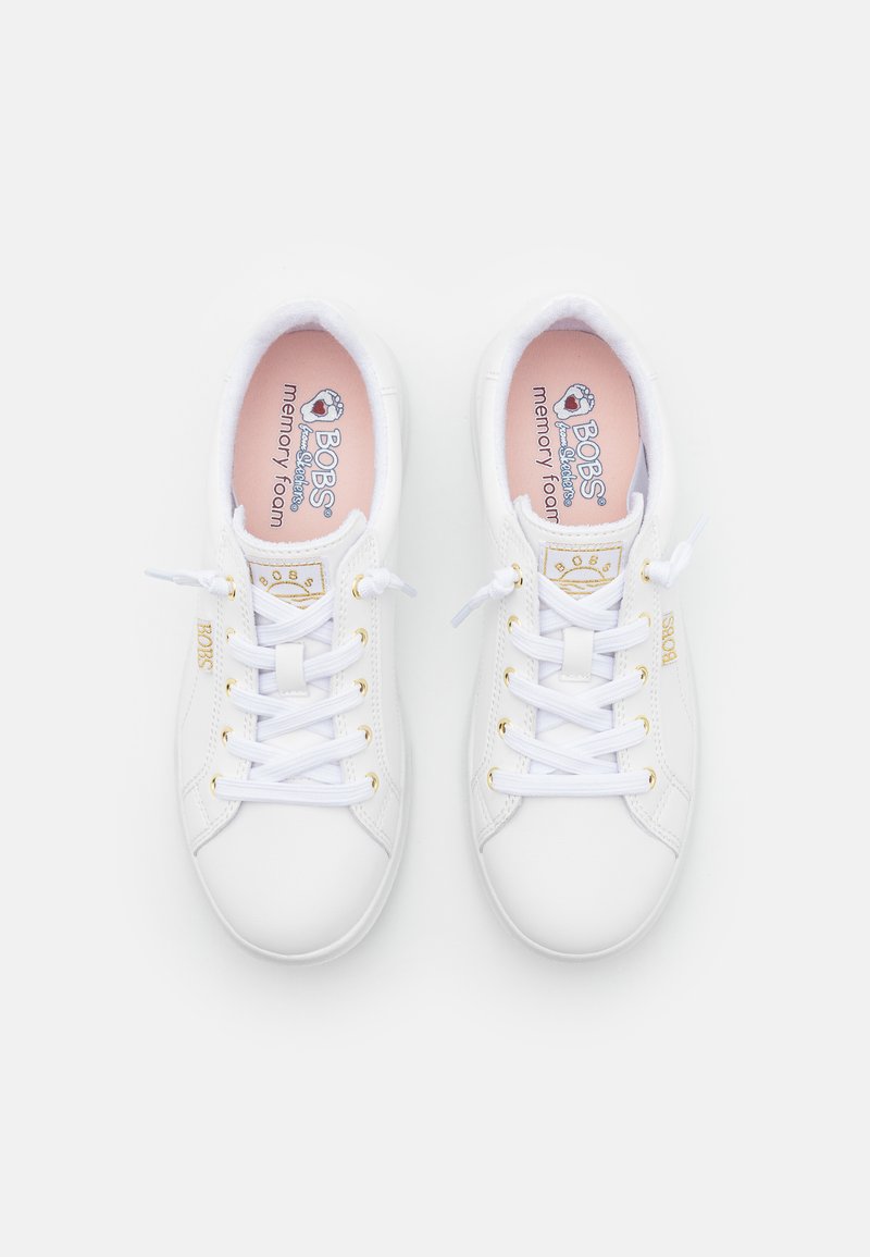 Zapatillas blancas con cordones, con una textura lisa similar al cuero, detalles en dorado y una plantilla en rosa claro etiquetada como "espuma de memoria BOBS".