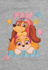 T-shirt grafico con due cani dei cartoni. Uno indossa un casco rosso, mentre l'altro ha una fascia rosa. Sfondo grigio con testo colorato e impronte di zampa.