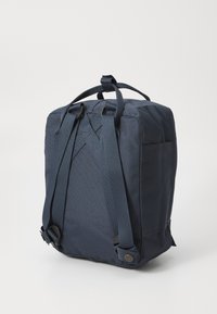 Marinblå ryggsäck i slitstarkt material med justerbara remmar, rektangulär form och en liten sidoficka. Minimalistisk design.