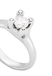 Anillo de plata con una piedra preciosa central clara sujeta por cuatro garras, banda suave, acabado pulido y bordes redondeados.