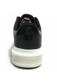 Sneaker nera con finitura in pelle lucida, suola bianca e accenti in mesh sul tallone. Presenta un logo circolare sul retro.