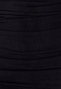 Melna ribota auduma ar savilktu tekstūru, horizontālām līnijām, vienmērīgu krāsu un mīkstu, elastīgu kvalitāti.