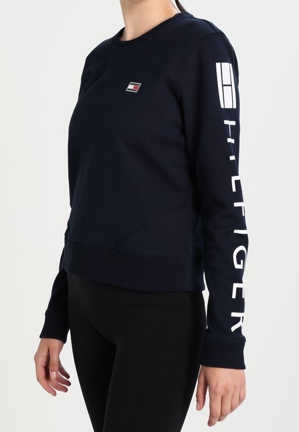 Felpa blu navy con collo a giro, polsini a costine e un piccolo logo sul petto, accompagnato da una scritta bianca audace lungo la manica.