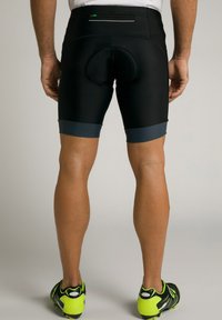 Sorte cykelshorts med polstret sæde, med en kontrast grå talje og manchetter. Udstyret med klare grønne atletiske sko.