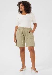 Khaki cargoshorts med två framfickor, resårmidja och dragsko. Matchat med en figurnära vit kortärmad topp och sandaletter.