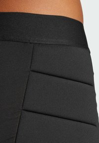 Schwarze Sportshorts mit einem breiten Taillenbund und strukturiertem, gestepptem Design. Der Stoff wirkt dehnbar und glatt.