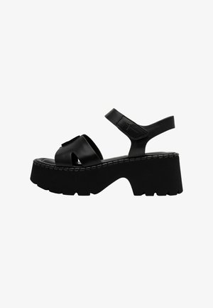 Black platform sandals with a chunky sole, featuring crossed leather straps and an adjustable ankle strap for a secure fit.